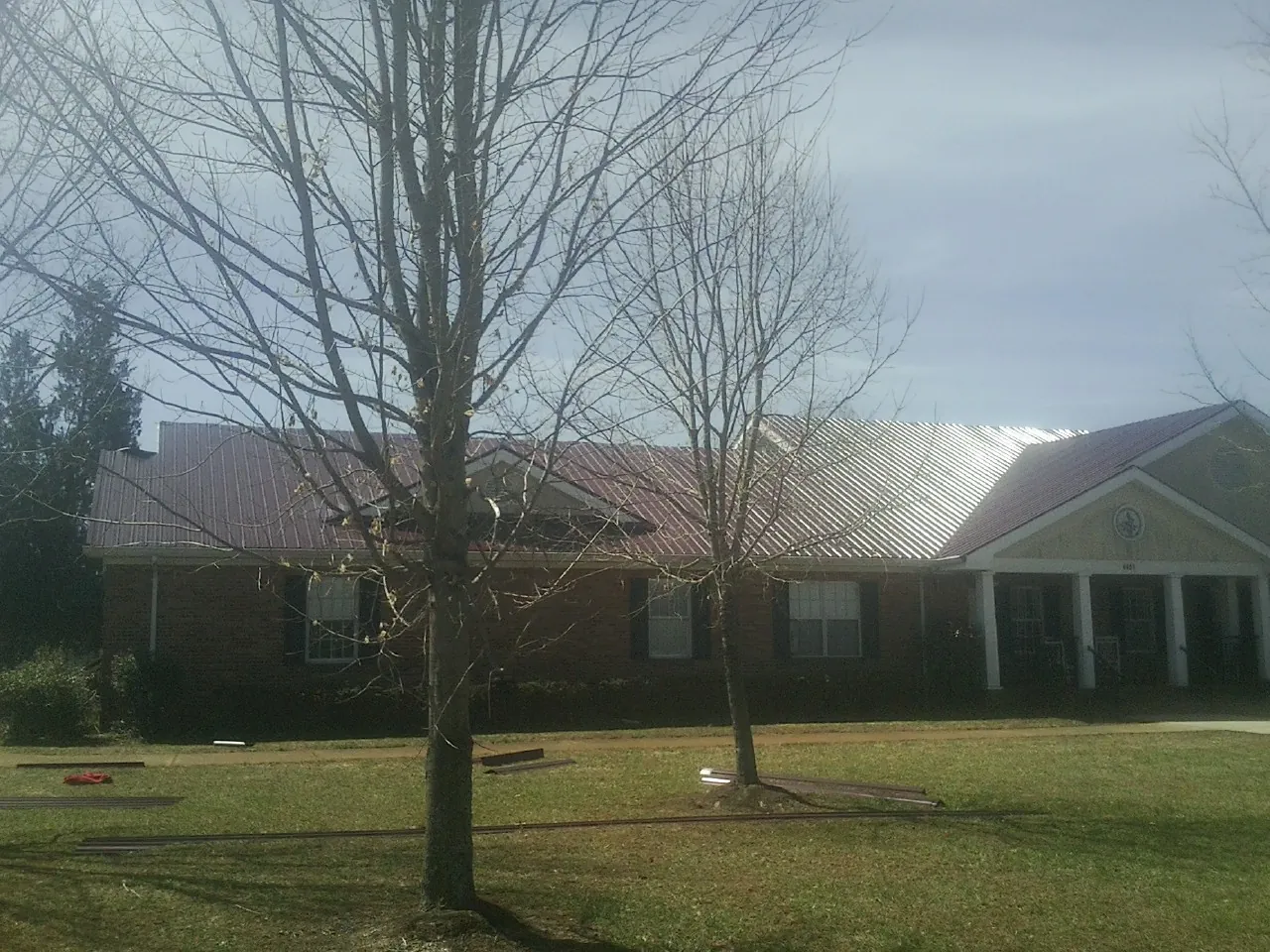 Red metal roof on a brick building seen from the front lawn in Hiddenite