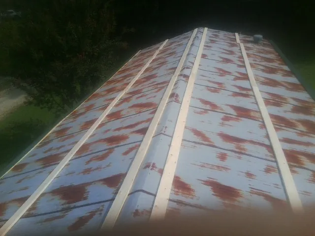 Rusted metal roof panels with new wood purlins before replacement — Storm Damage Roof Repair in Hiddenite by Roofing Brothers
