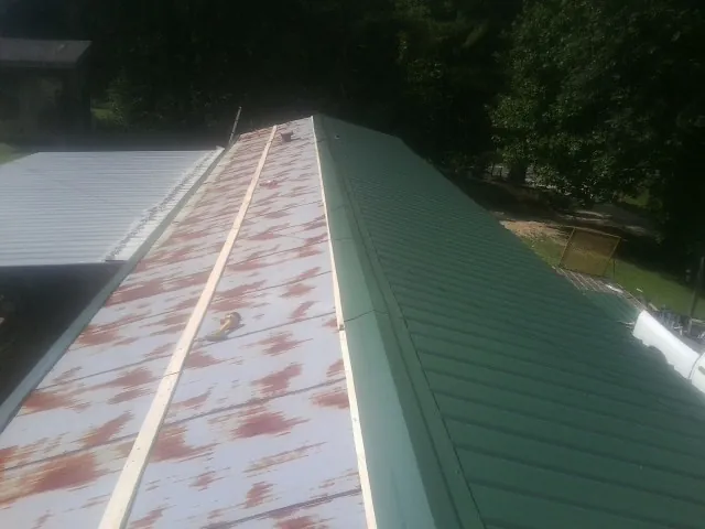 Old rusted panels beside newly installed green metal roofing — Wind Damage Roof Repair by Roofing Brothers in Hiddenite