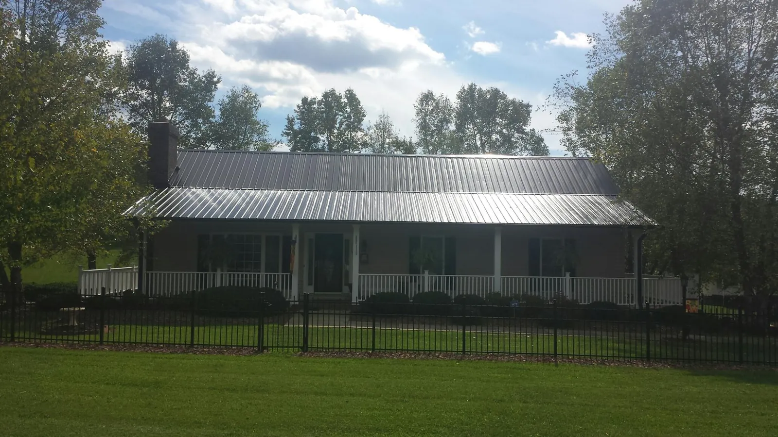 Gray metal roof on a brick ranch with a full width front porch — Gutter Guard Installation work by our crew in Hiddenite