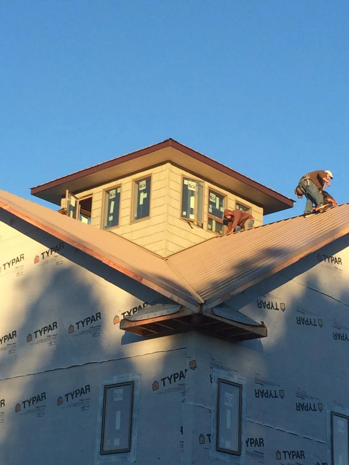 Roofers working around a rooftop cupola on a new metal roof at sunset — Roof Waterproofing in Hiddenite by Roofing Brothers